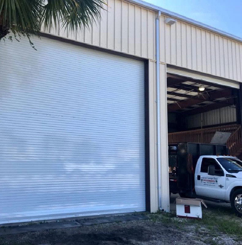 White truck parked in front of a building with a roll up garage door